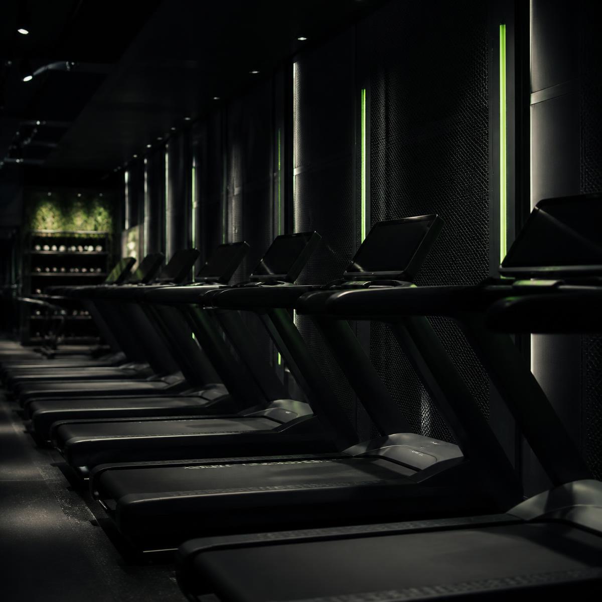 Imagen conceptual de una zona de cardio con cintas de correr en penumbra